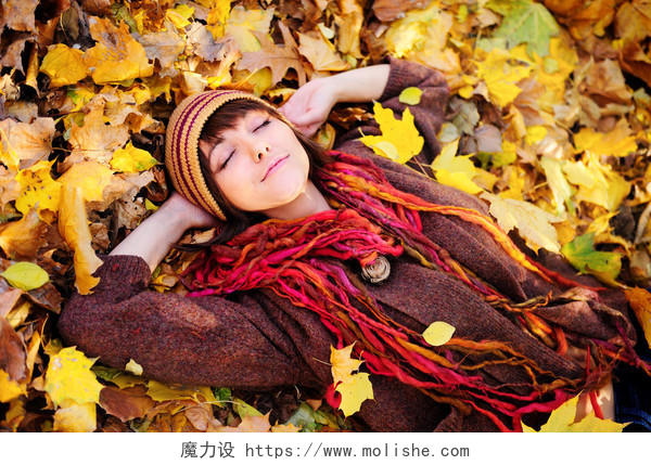 躺在秋天落叶堆上的漂亮女孩放松